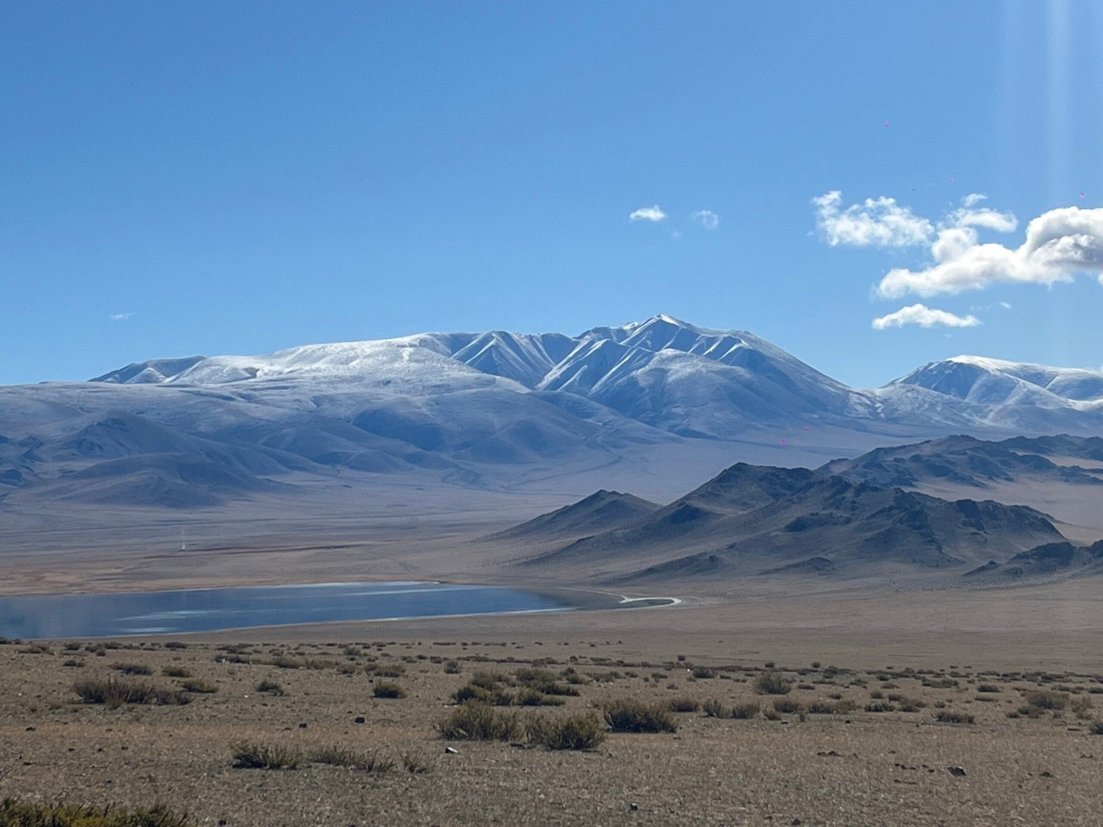 Snow-capped Altai Mountains with lake in western Mongolia where altitude sickness is a risk for travelers