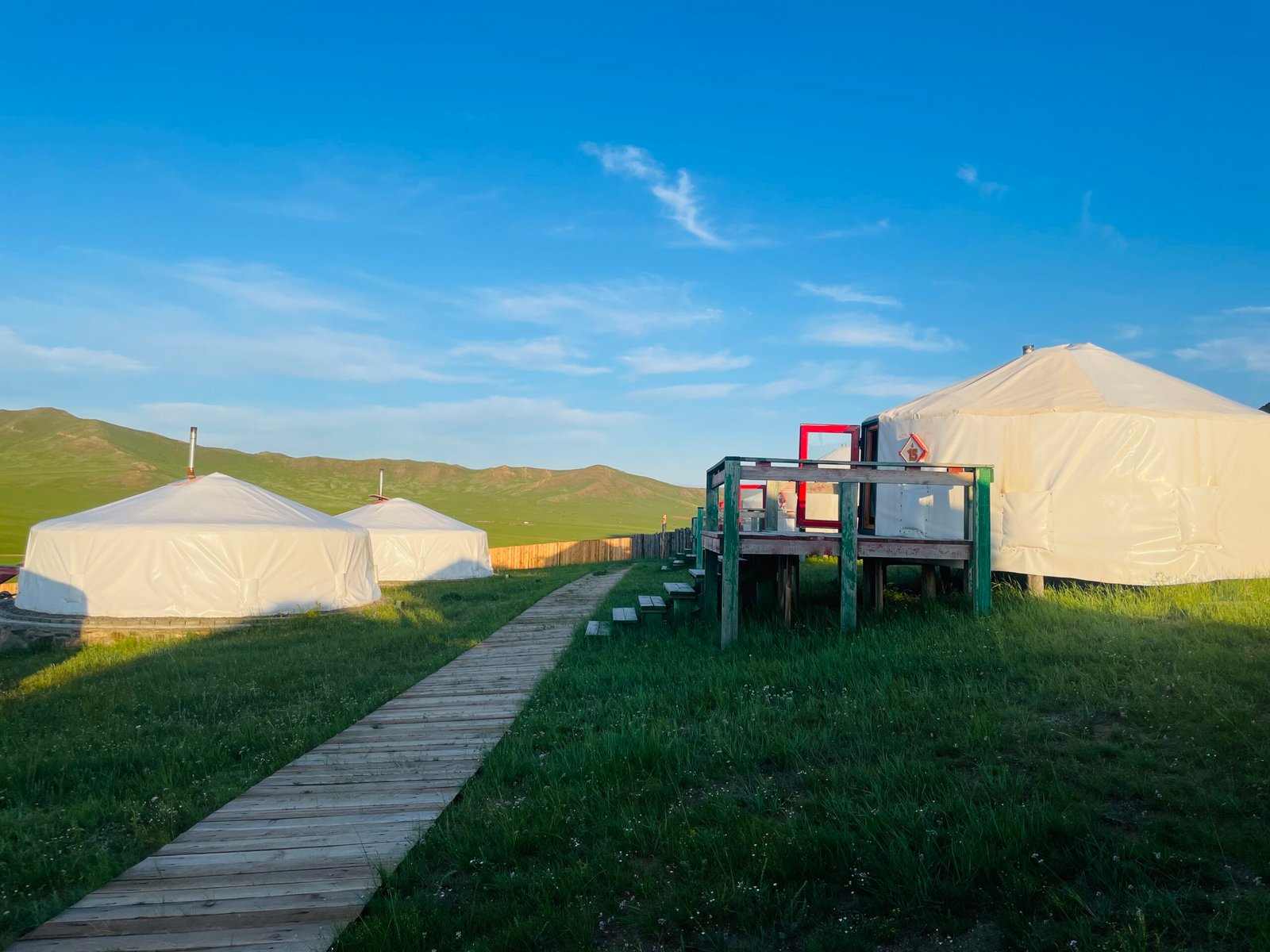 Traditional ger camp boardwalk deck overlooking green steppe Mongolia
