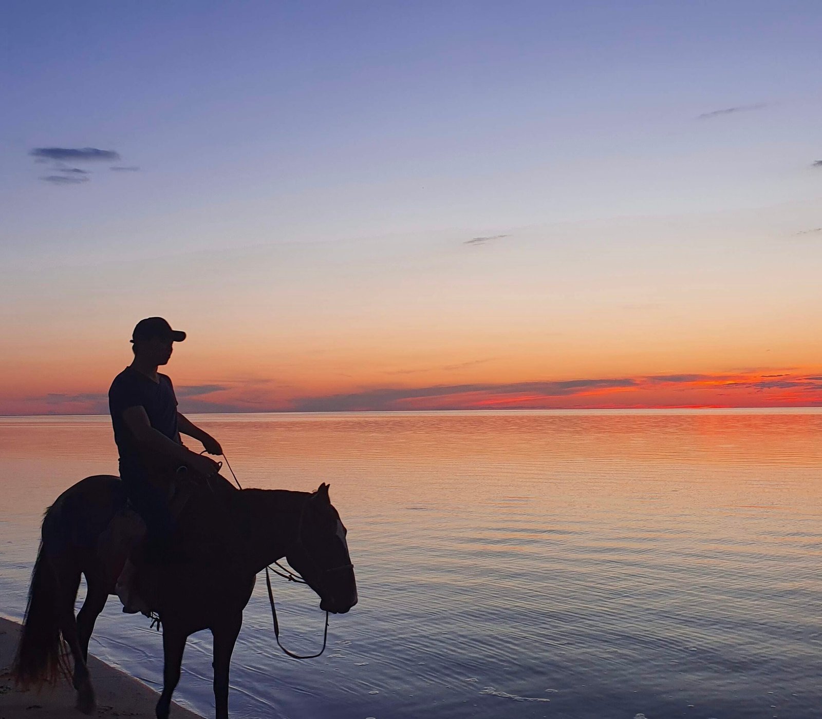 Mongolian rider on horseback silhouetted against lake sunset steppe