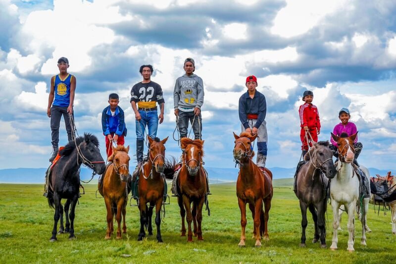 Mongolian children standing on horseback on open steppe — Mongolia Family Adventure Tour