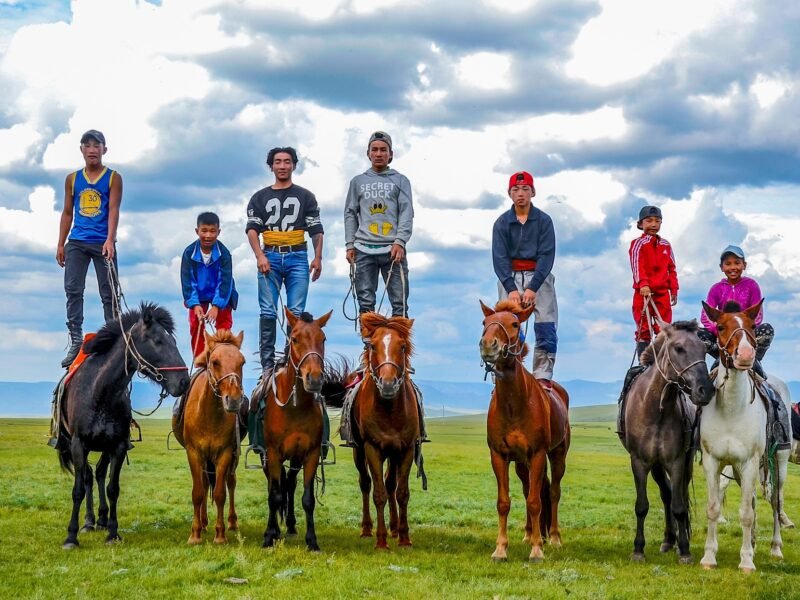 Mongolian children standing on horseback on open steppe — Mongolia Family Adventure Tour