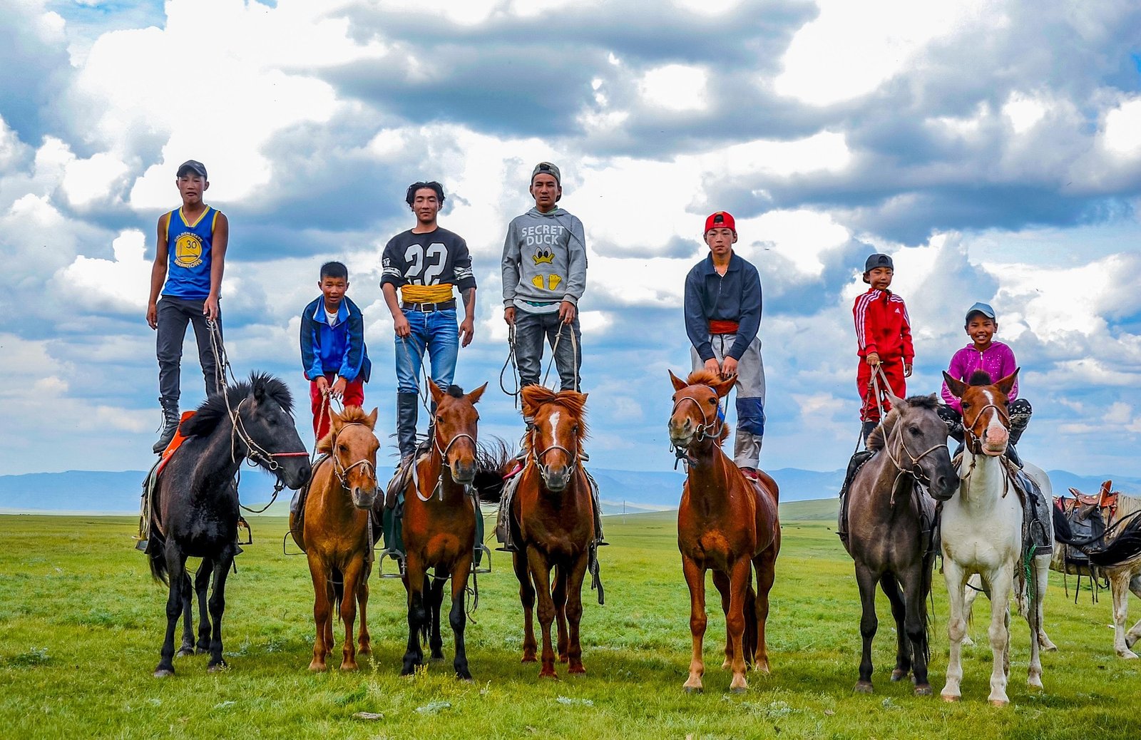 Mongolian children standing on horseback on open steppe — Mongolia Family Adventure Tour