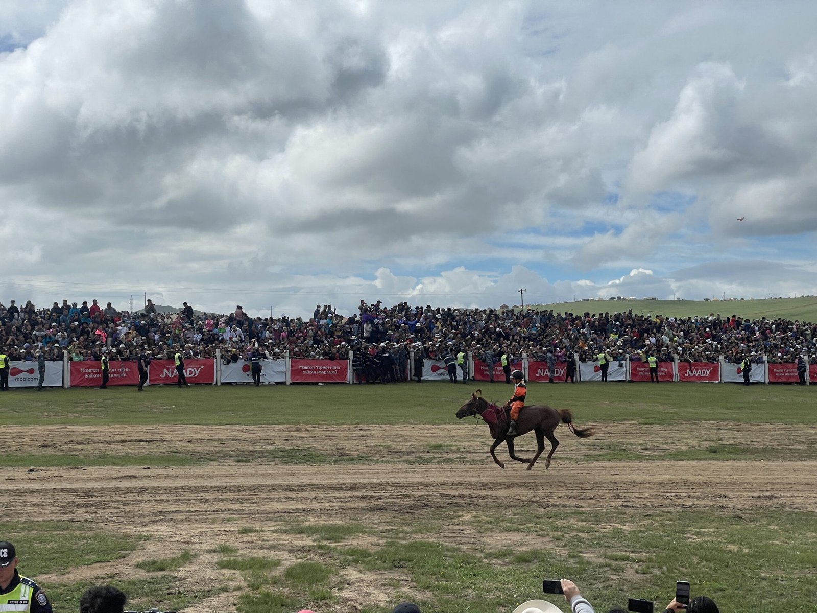 Crowd watching horses cross the finish line at a Naadam race