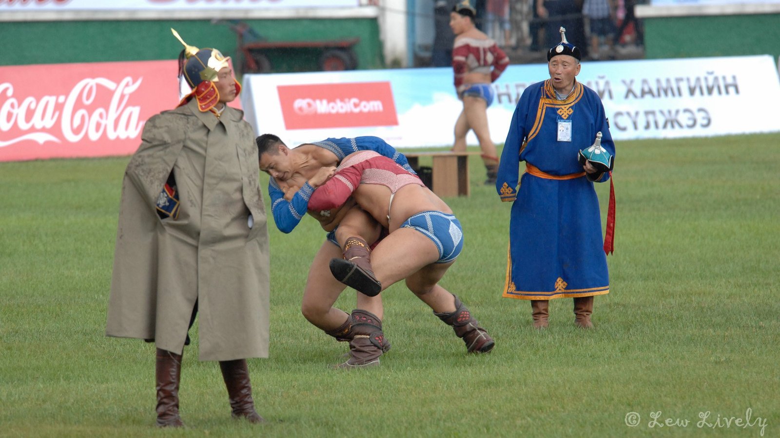 Two Mongolian wrestlers in zodog jackets grapple during a Naadam bout